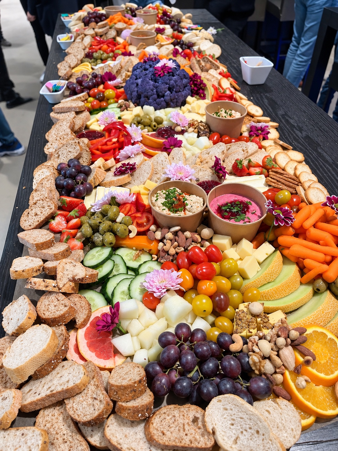 A Well grazing table with bread, dips, vegetables, fruit and flowers